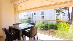 A balcony with a table and chairs, a view of a building, and a glass railing. - SanPietro Vacation Apartment 050 (Plazhi San Pietro)