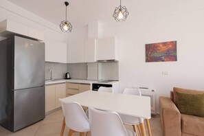 Eine moderne Küche mit Kühlschrank, Schränken und einem Esstisch mit Stühlen.