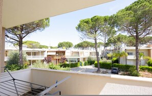 A residential area with multiple apartment buildings, a balcony with a metal railing, and a car parked in the driveway. - Lura Apartment 07 in Plazhi San Pietro (Plazhi San Pietro)