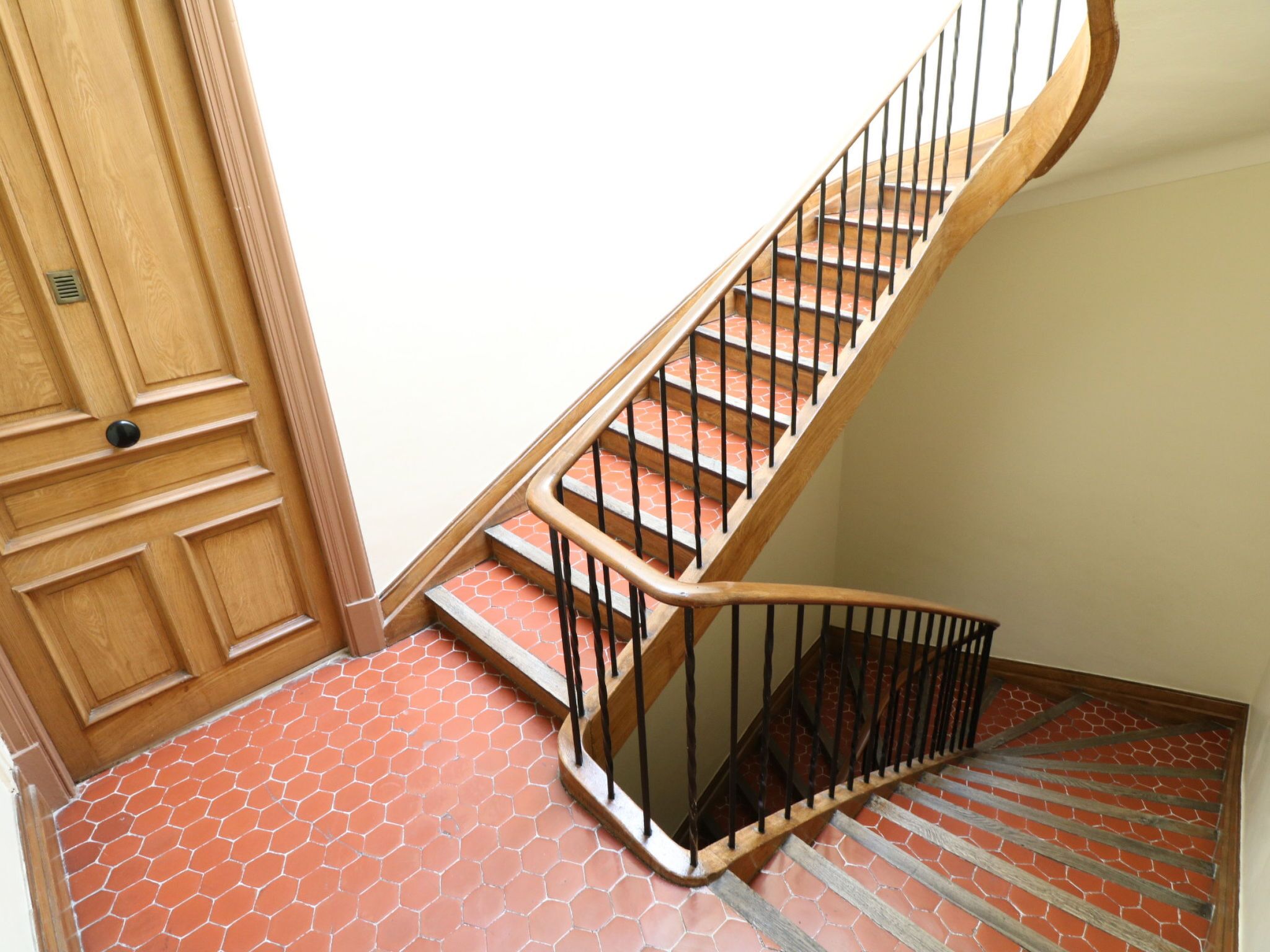 A wooden staircase with a metal railing leading to a landing.