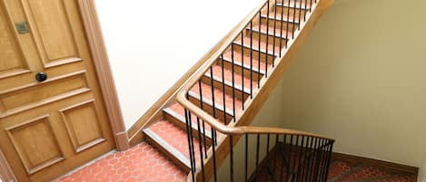 A wooden staircase with a metal railing leading to a landing.
