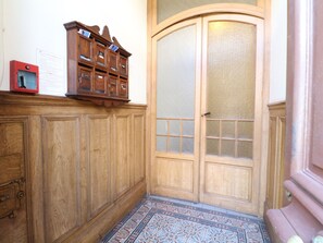 A wooden cabinet with multiple compartments, a door with glass panels, and a patterned floor. - Apartment  by Interhome (Cannes)