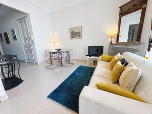 Ein modernes Wohnzimmer mit Sofa, Fernseher und Essbereich mit Stühlen und Tisch.