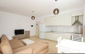 Ein modernes Wohnzimmer mit Sofa, Fernseher und Essbereich.
