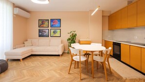 Ein modernes Wohnzimmer mit einer Couch, einem Esstisch, Stühlen und Kunstwerken an der Wand.