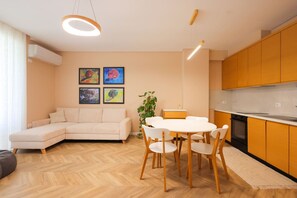 A modern living room with a sofa, dining table, chairs, and artwork on the wall. - SanPietro Vacation Apartment 053 (Plazhi San Pietro)