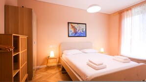 Ein Schlafzimmer mit Bett, Nachttischlampen, einem Kleiderschrank und einem Bild an der Wand.