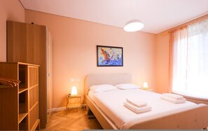 A bedroom with a bed, bedside lamps, a wardrobe, and a painting on the wall. - SanPietro Vacation Apartment 053 (Plazhi San Pietro)
