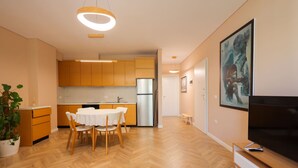 Eine moderne Küche mit Holzausstattung, einem Edelstahlkühlschrank und einem Essbereich mit weißem Tisch und Stühlen.