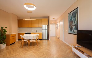 A modern kitchen with wooden cabinets, a stainless steel refrigerator, and a dining area with a white table and chairs. - SanPietro Vacation Apartment 053 (Plazhi San Pietro)