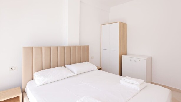 A bedroom with a bed, a wardrobe, and a small white cabinet. - Sunny Apartment, Balcony & Beach Access (Plazhi San Pietro)