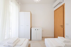 A bedroom with two beds, a wardrobe, a cabinet, and a wooden door. - Lura Apartment 06 in Plazhi San Pietro (Plazhi San Pietro)