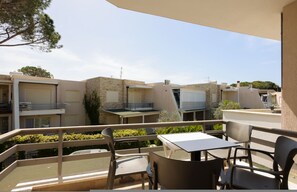 Un balcón con mobiliario exterior, vista a edificios vecinos y cielo despejado.