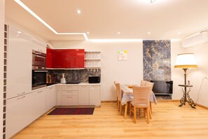 A modern kitchen with white cabinets, red accents, and a dining area with a table and chairs. - SanPietro Vacation Apartment 054 (Plazhi San Pietro)