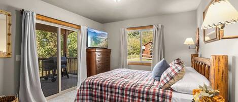 A bedroom with a bed, a dresser, a nightstand, a lamp, and a window with curtains.