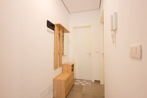 A hallway with a wooden bench, a door, and a phone on the wall. - Boho-Chic Apartment with Garden Views (Plazhi San Pietro)