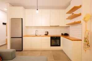 A modern kitchen with white cabinets, a stainless steel refrigerator, a built-in oven, and a wooden countertop. - Boho-Chic Apartment with Garden Views (Plazhi San Pietro)