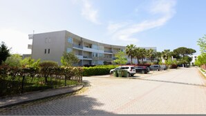 A multi-story building with balconies, a paved driveway, parked cars, and greenery. - Lura Apartment 04 in Plazhi San Pietro (Plazhi San Pietro)