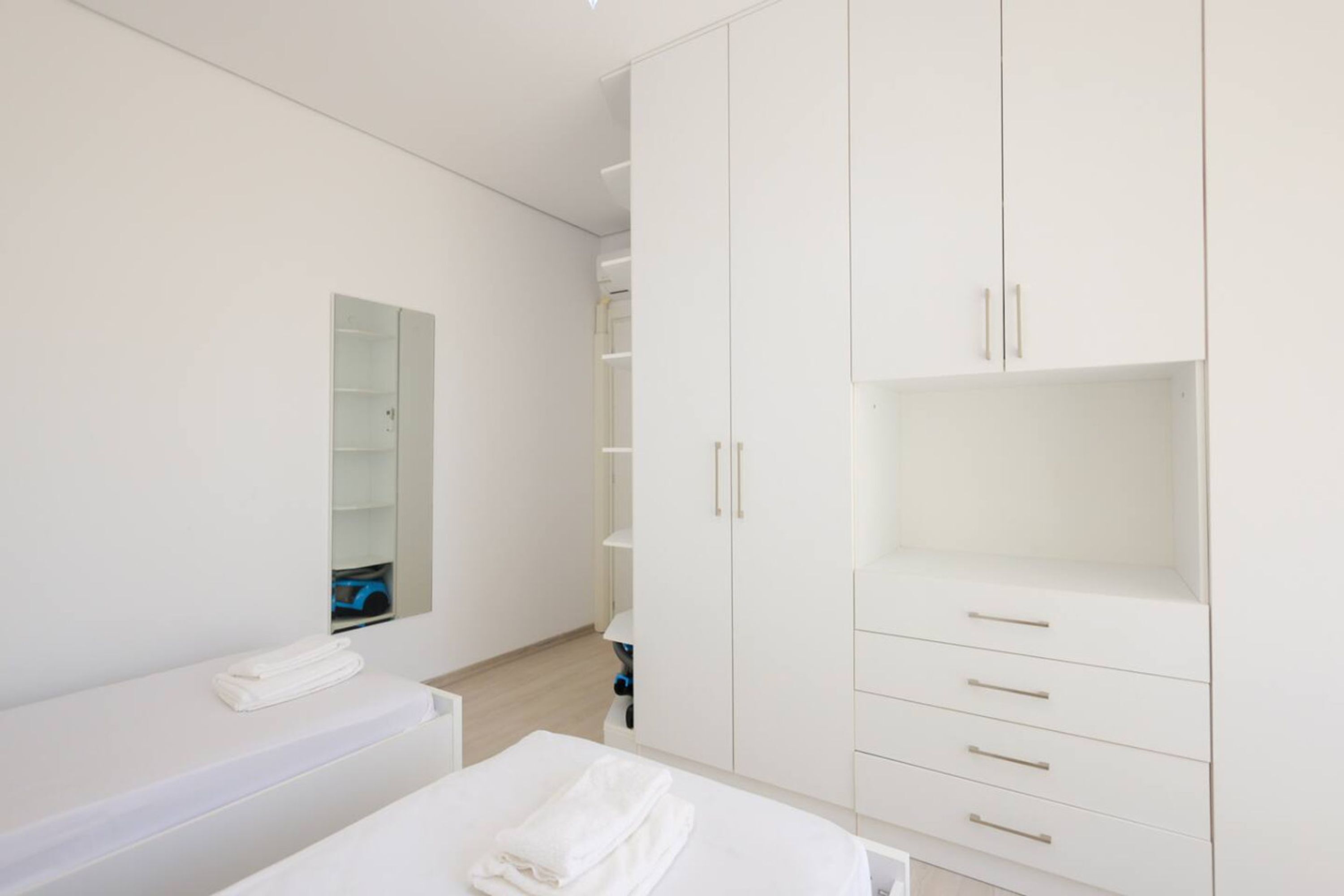 Een moderne slaapkamer met een bed, een witte kledingkast en een spiegel.