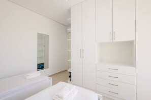 A modern bedroom with a bed, a white wardrobe, and a mirror. - SanPietro Vacation Apartment 051 (Plazhi San Pietro)