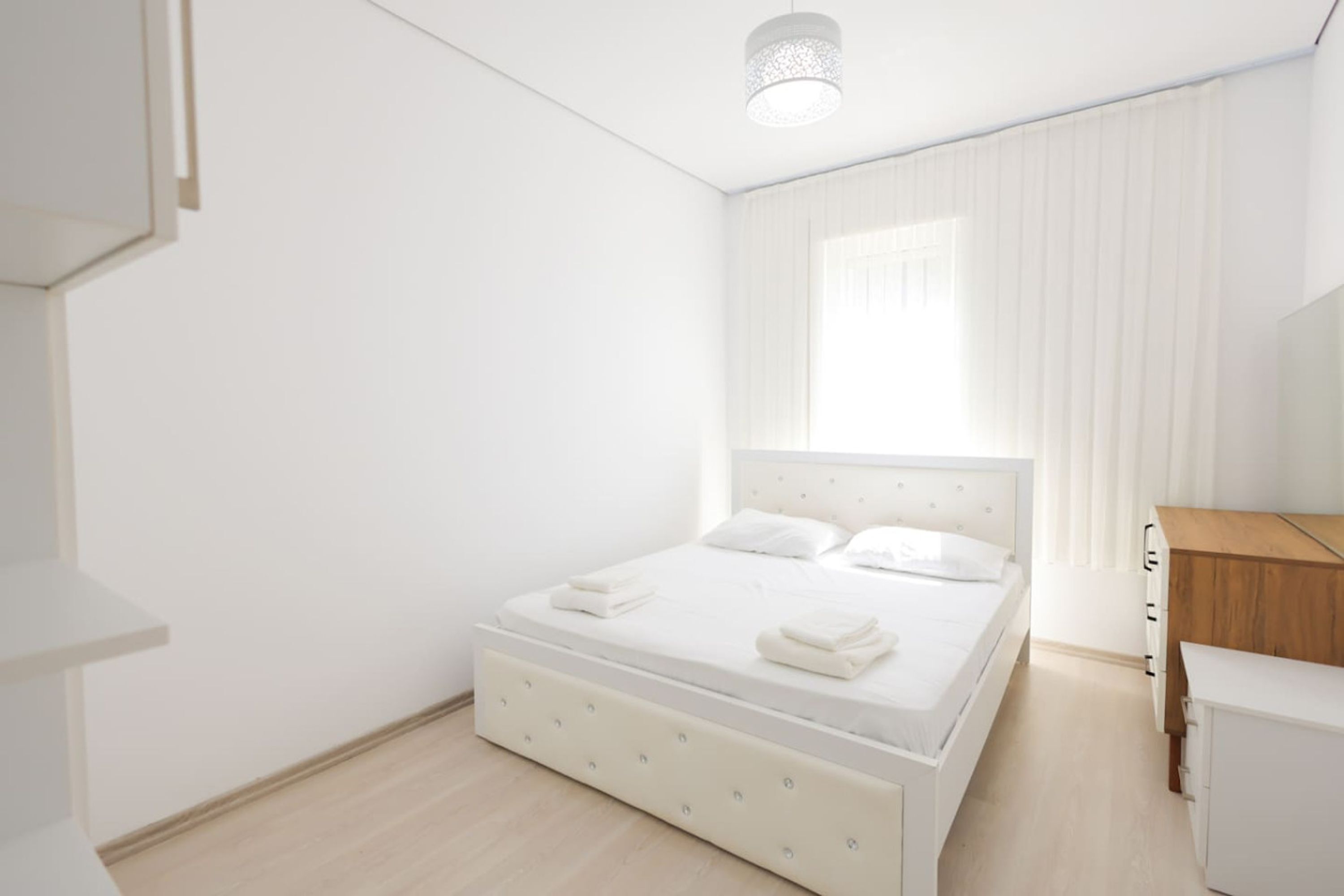 Una camera da letto con un letto, un comodino, un armadio e una finestra con tende.
