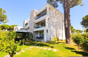 A modern two-story house with a balcony, a garden with a pathway, and a large tree. - SanPietro Vacation Apartment 051 (Plazhi San Pietro)