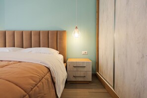 A bedroom with a bed, bedside table, and a hanging light fixture. - Colorful Apartment with Balcony | San Pietro (Plazhi San Pietro)