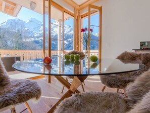 A room with a glass table, wooden chairs, a view of snow-capped mountains, and a wooden balcony railing. - Panoramapark Soleil Bietenhorn by Interhome (Lauterbrunnen)