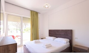 Una habitación de hotel con cama, mesita de noche, escritorio y vistas al exterior.