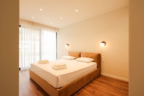 A hotel room with a large bed, two bedside lamps, and a window with curtains. - SanPietro Premium Villa 015 (Durrës)