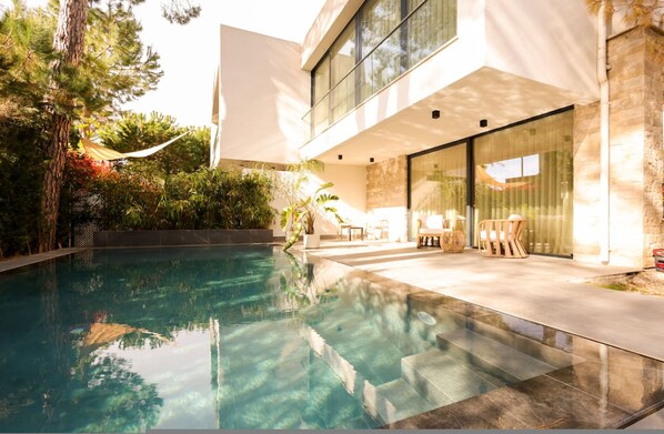 A modern house with a swimming pool, outdoor furniture, and a large glass door. - SanPietro Premium Villa 015 (Durrës)
