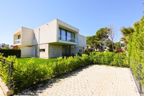 A modern two-story house with a paved driveway and a well-maintained garden. - Beach Resort Villa with Private Garden (Plazhi San Pietro)