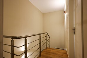 A staircase with a metal handrail and wooden steps, leading to a door with a white frame. - Beach Resort Villa with Private Garden (Plazhi San Pietro)