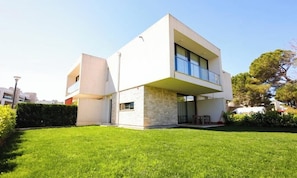 A modern two-story house with a flat roof, large windows, and a well-maintained lawn. - Beach Resort Villa with Private Garden (Plazhi San Pietro)