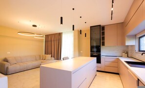 Eine moderne Küche mit Kochinsel, Essbereich mit einer Couch und einem großen Fenster für natürliches Licht.