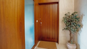 Eine Holztür mit Griff und Schlüsselloch, eine Fußmatte und ein Blumentopf mit grünen Blättern.