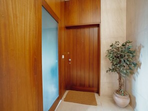 Eine Holztür mit Griff und Schlüsselloch, eine Fußmatte und ein Blumentopf mit grünen Blättern.