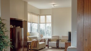 Ein Wohnzimmer mit einer Couch, Sesseln, einem Couchtisch, einem Fernseher und einem Bücherregal.