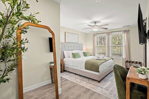 A bedroom with a bed, a ceiling fan, a TV, and a window with curtains. - Black Mtn 3BR House - Private Yard with Mtn Views (Black Mountain)