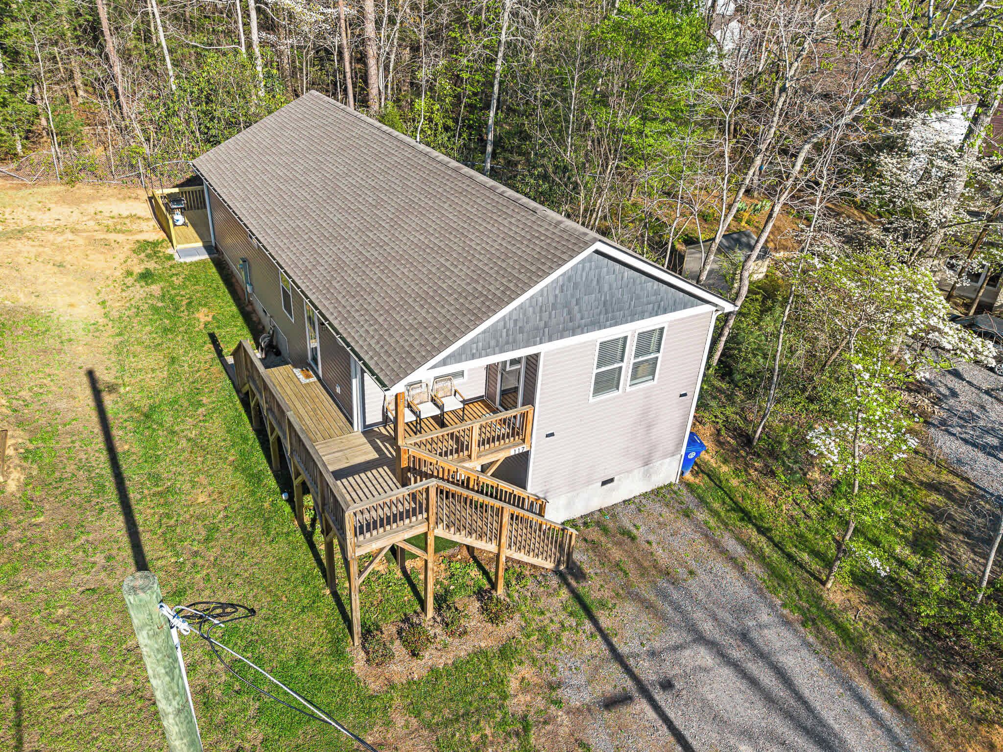 A single-story house with a deck, surrounded by trees.