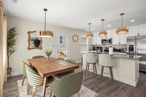 A modern kitchen with stainless steel appliances, a wooden dining table, and a bar area. - Black Mtn 3BR House - Private Yard with Mtn Views (Black Mountain)