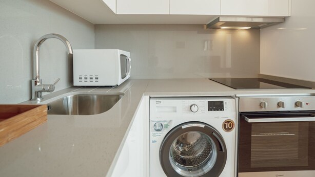 A modern kitchen with a washing machine, a microwave, and a stove. - Apartment  by Interhome (Porto)