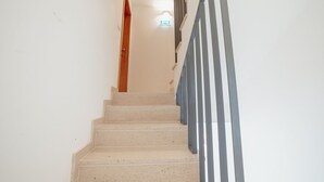 A staircase with a wooden door at the top and a metal railing on the right. - Apartment  by Interhome (Porto)
