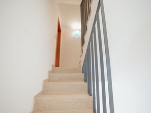 Una escalera con una puerta de madera en la parte superior y una barandilla metálica a la derecha.