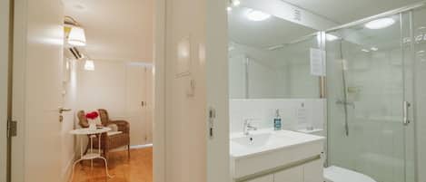 A modern bathroom with a glass shower enclosure, a white sink, and a toilet.