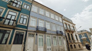 Un edificio de varios pisos con fachada de tejas, varios balcones y vista a la calle.