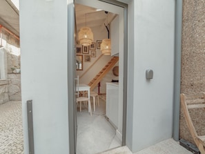 Un passage donnant sur un espace repas avec une table et des chaises, un escalier et des luminaires fixés au mur.