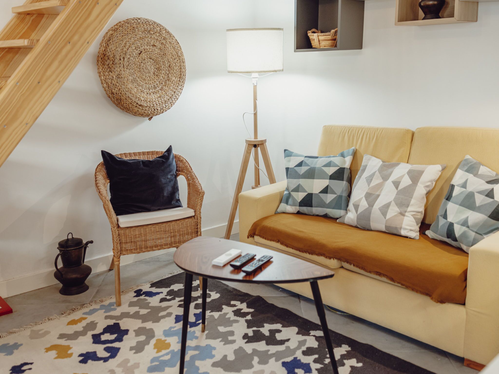 Una sala de estar con un sofá, una silla, una lámpara de pie y un tapete estampado.