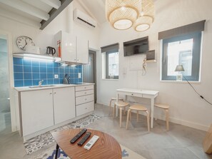 Een moderne keuken met witte kastjes, een blauwe spatwand, en een eethoek met een tafel en stoelen.