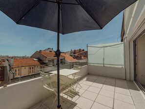 A balcony with a table and chairs, a large umbrella, and a view of the cityscape. - Apartment  by Interhome (Porto)